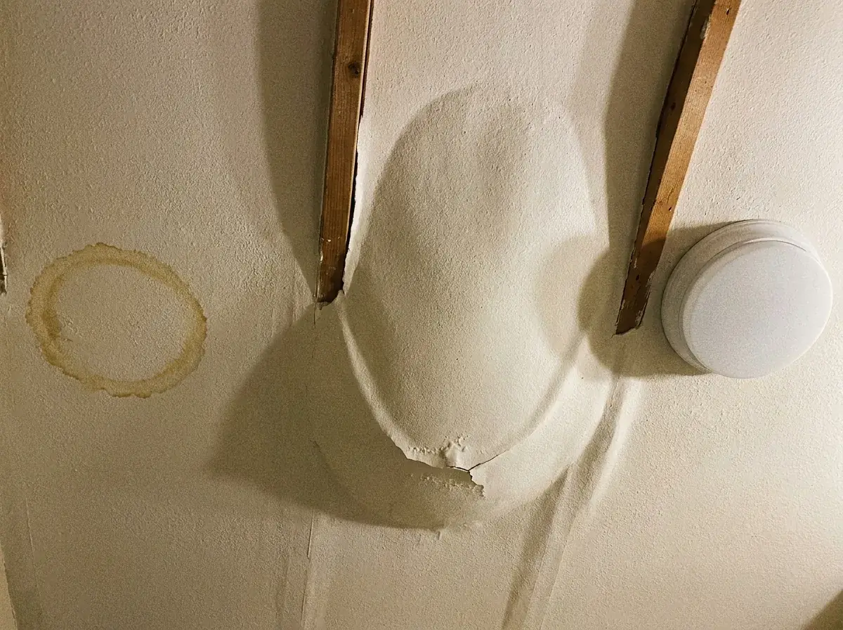 Drywall Damage Repair: What’s Causing It and How to Fix It 3 Bathroom ceiling with a sagging section and a brown water ring stain indicating drywall should be replaced.